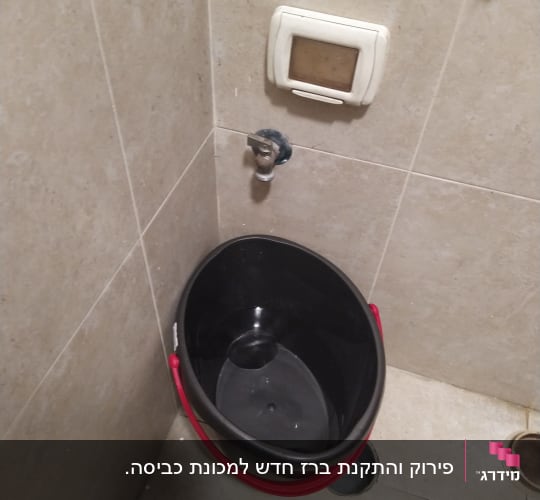 דלי שחור עם ידית אדומה ליד ברז קיר